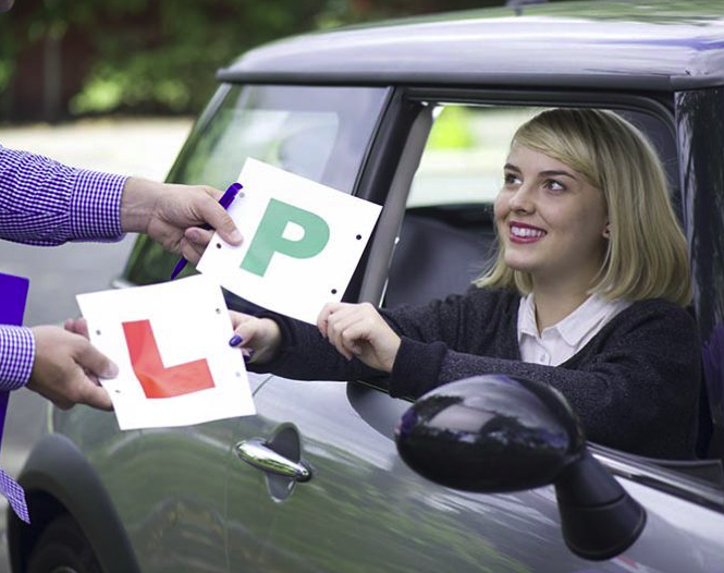 Learner driver swapping L plates for P plates with instructor